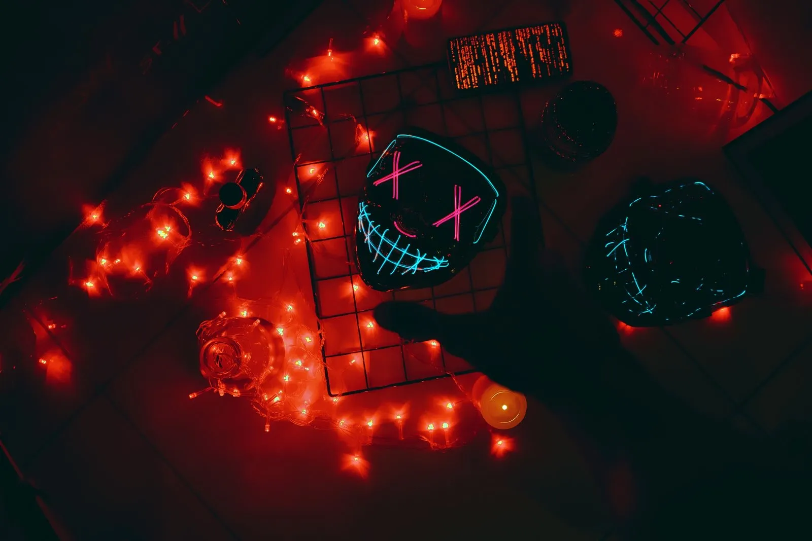 Máscara LED de Halloween rodeada de luces rojas y decoración en la oscuridad