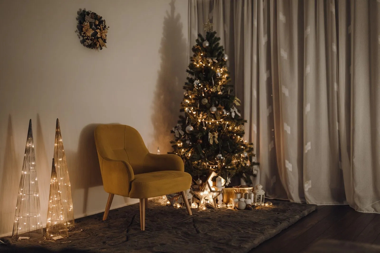 Árbol de Navidad con luces LED cálidas junto a un sillón amarillo y conos luminosos