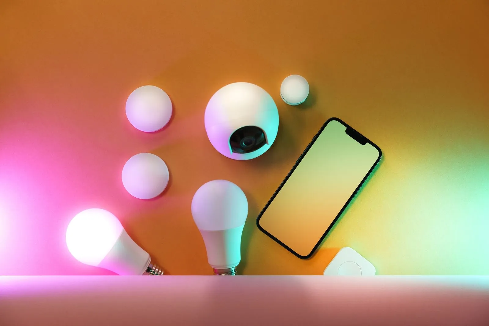 Bombillas inteligentes, sensores y un móvil con luz de colores sobre una mesa