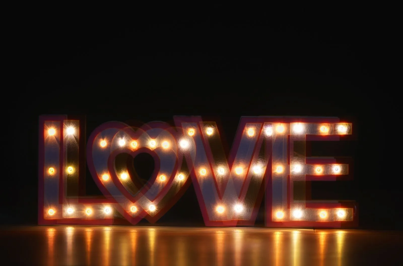 Letras luminosas con la palabra love y un corazón encendidas en la oscuridad