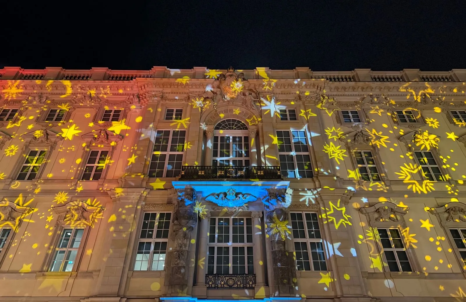 Fachada de un edificio con estrellas doradas proyectadas por un proyector de luces navideño