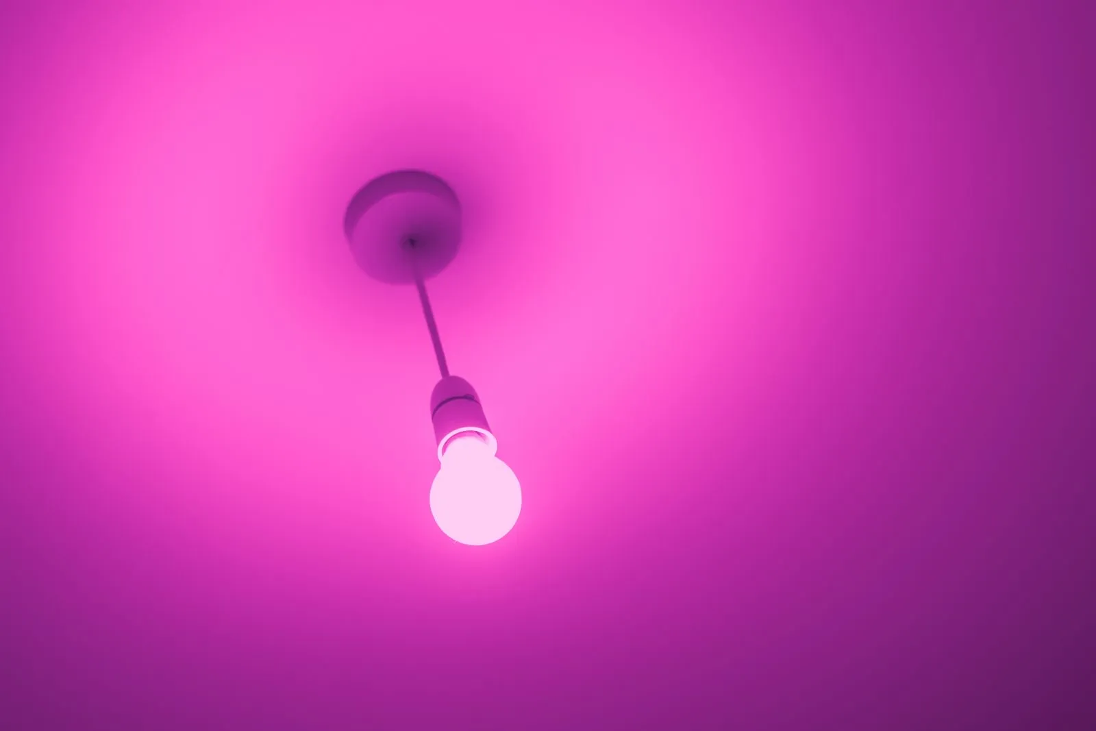 Bombilla inteligente de color colgada del techo que tiñe la habitación de rosa