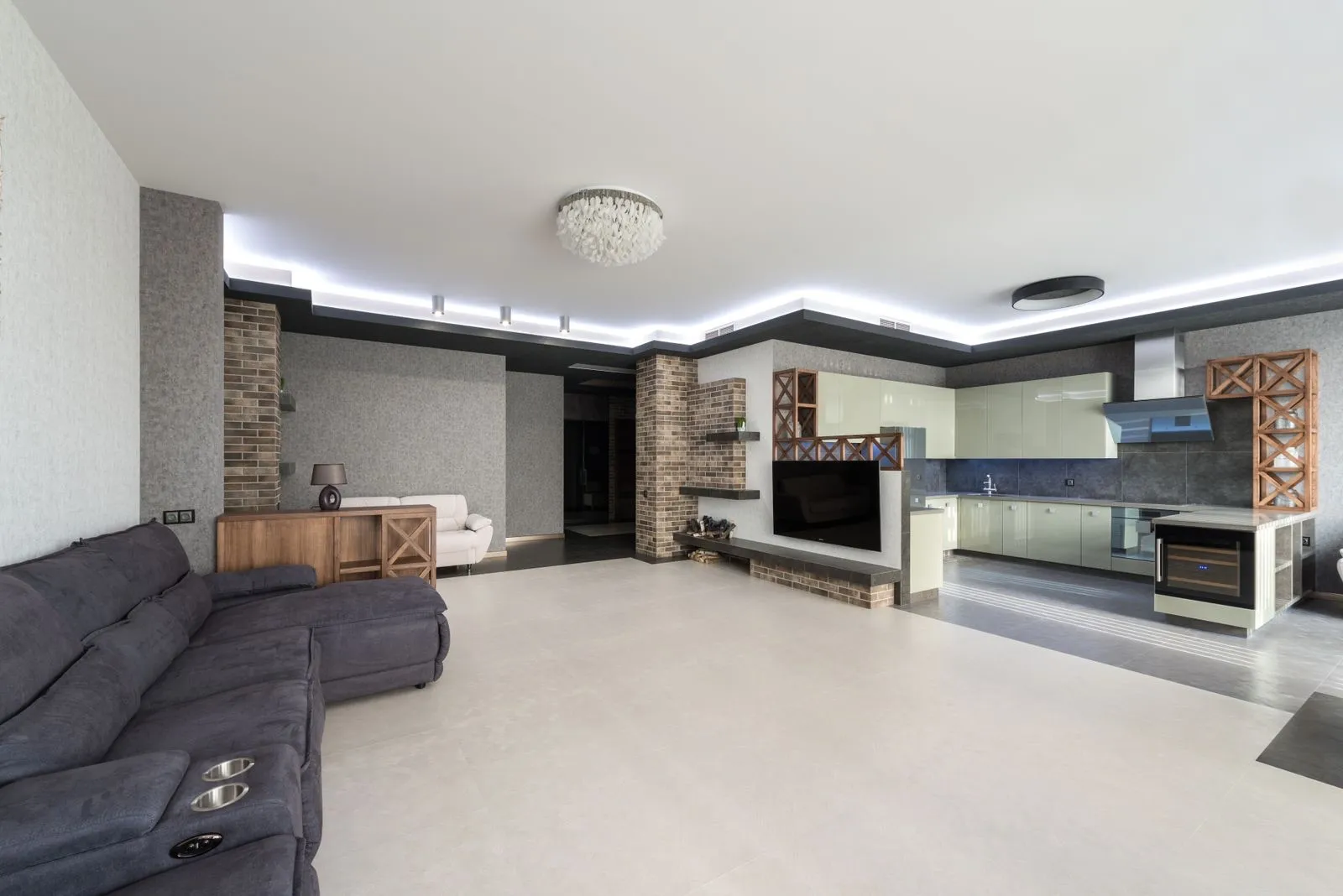 Salón amplio con tira LED fría en el techo y sofá junto a la cocina