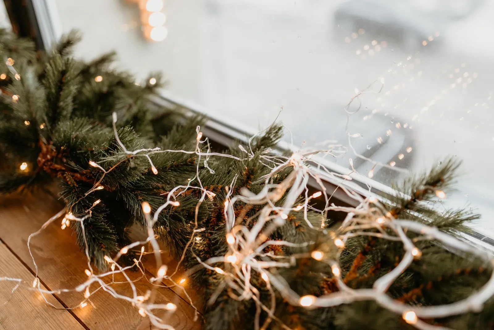 Guirnalda de pino con microluces LED blancas sobre el alféizar de una ventana
