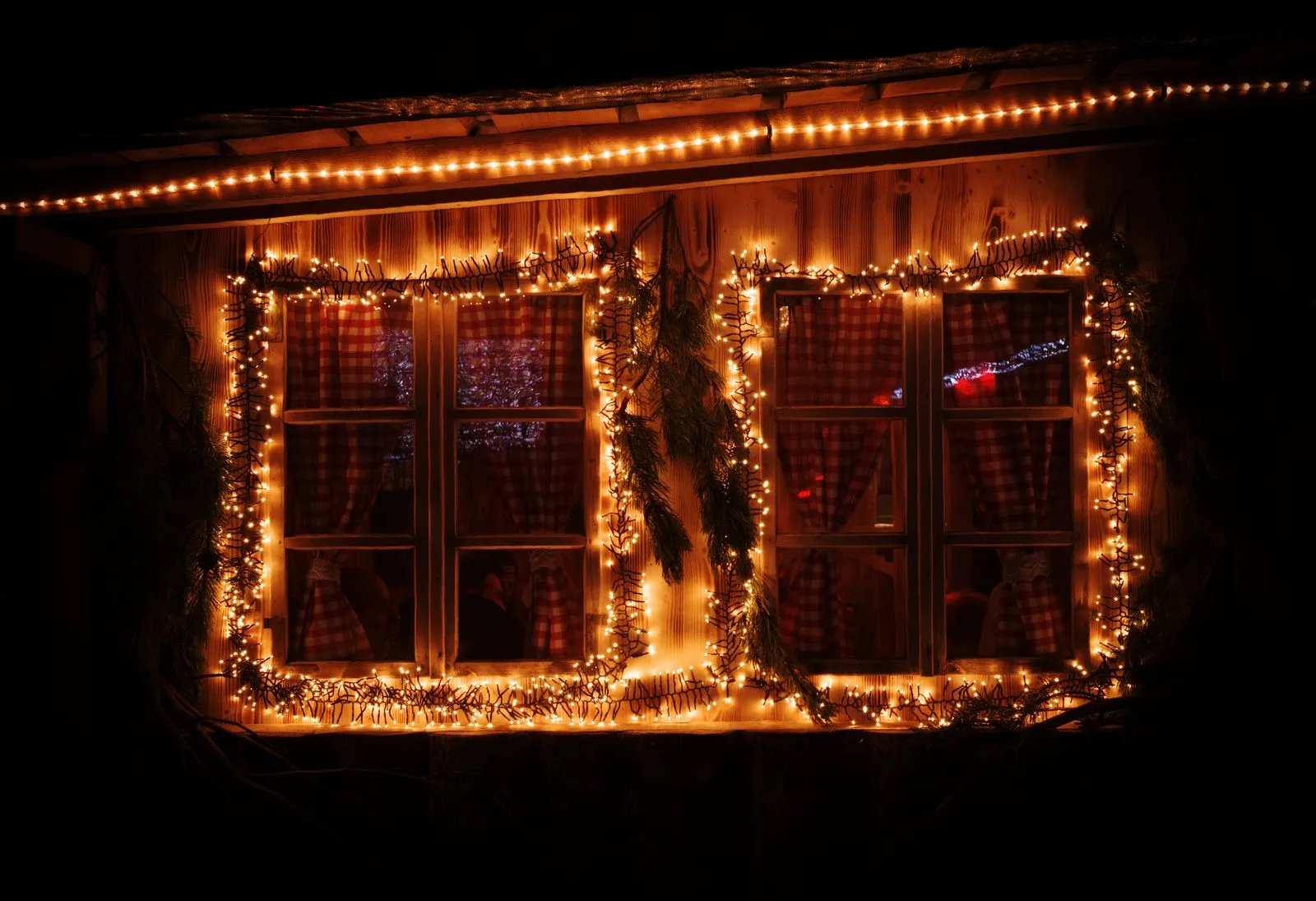 Dos ventanas de madera enmarcadas con luces LED cálidas en una noche de invierno