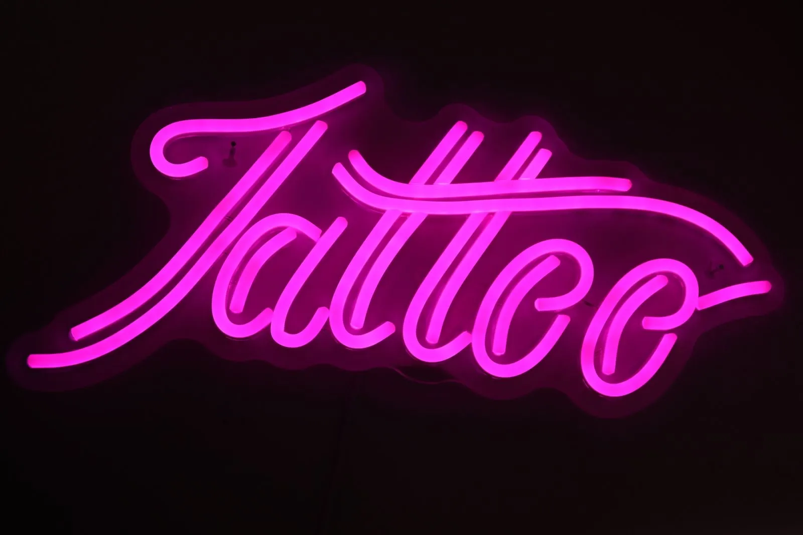 Letras de neón LED fucsia en letra cursiva sobre un fondo negro