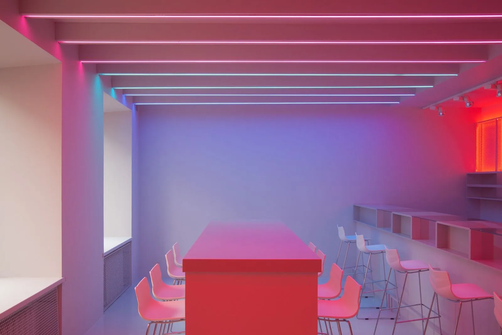 Techo con líneas de tiras LED que bañan la sala en tonos rosa y azul